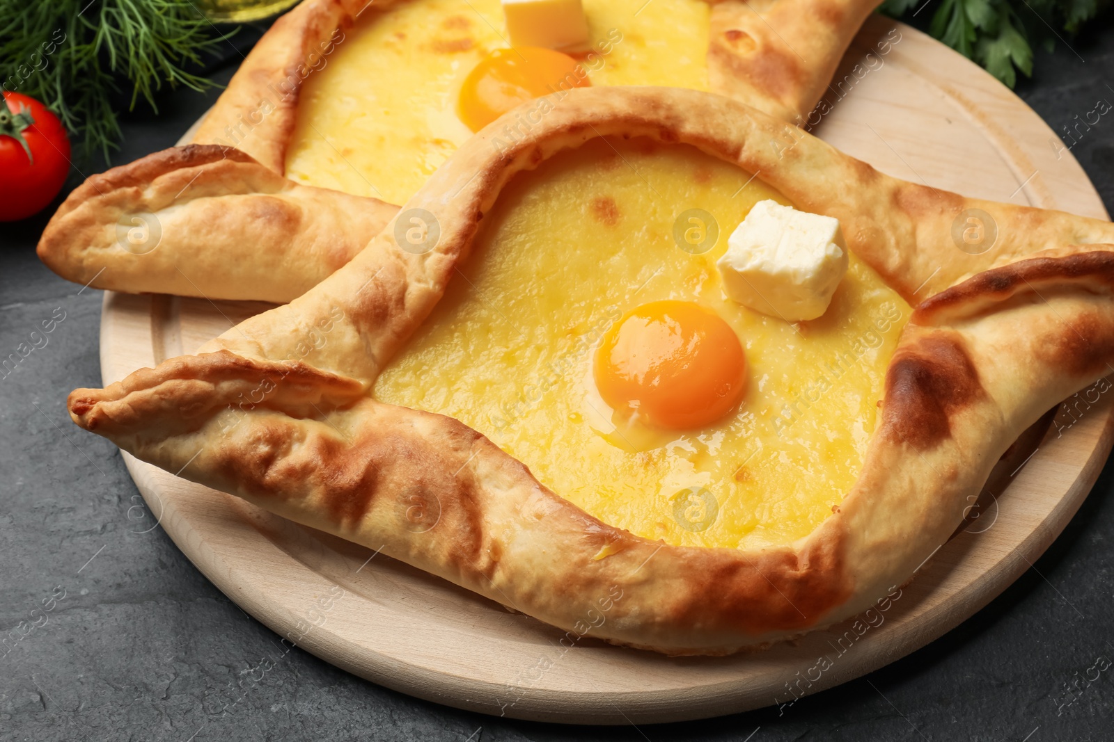 Tasty khachapuri with cheese, egg and other products on black table, closeup Photo of Tasty khachapuri with cheese, egg and other products on black table, closeup