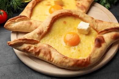 Photo of Tasty khachapuri with cheese, egg and other products on black table, closeup