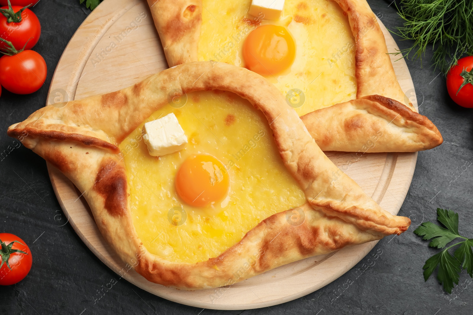 Tasty khachapuri with cheese, egg and other products on black table, flat lay Photo of Tasty khachapuri with cheese, egg and other products on black table, flat lay