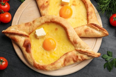 Photo of Tasty khachapuri with cheese, egg and other products on black table, flat lay