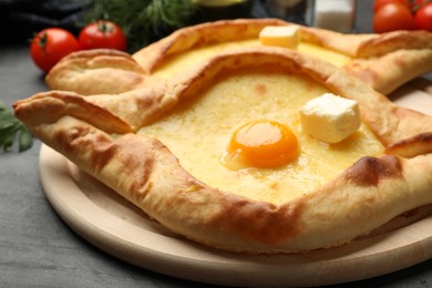 Photo of Tasty khachapuri with cheese, egg and other products on black table, closeup