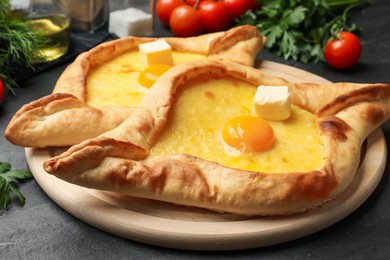 Photo of Tasty khachapuri with cheese, egg and other products on black table, closeup