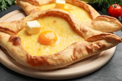 Photo of Tasty khachapuri with cheese, egg and other products on black table, closeup