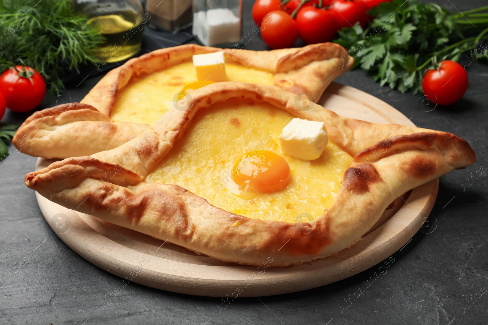 Tasty khachapuri with cheese, egg and other products on black table, closeup Photo of Tasty khachapuri with cheese, egg and other products on black table, closeup