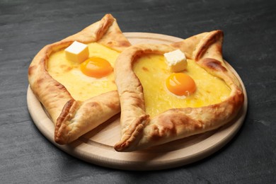 Photo of Tasty khachapuri with cheese and egg on black table, closeup