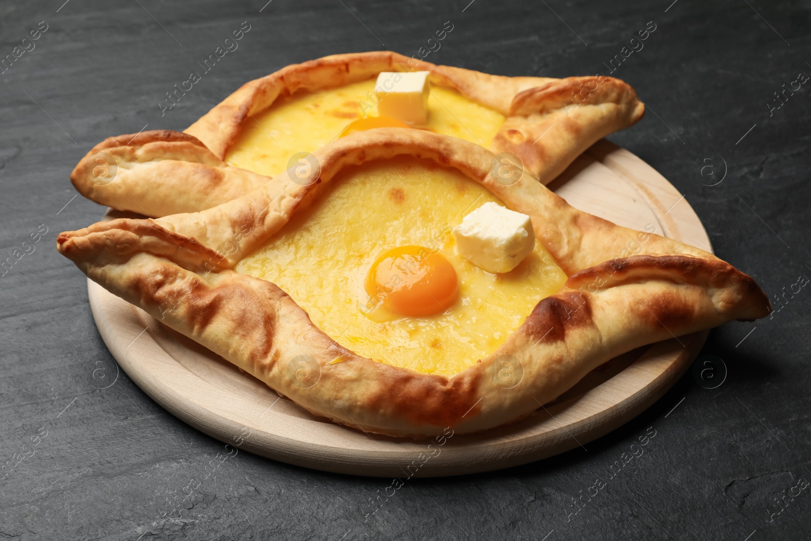 Tasty khachapuri with cheese and egg on black table, closeup Photo of Tasty khachapuri with cheese and egg on black table, closeup