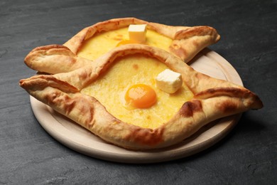Photo of Tasty khachapuri with cheese and egg on black table, closeup