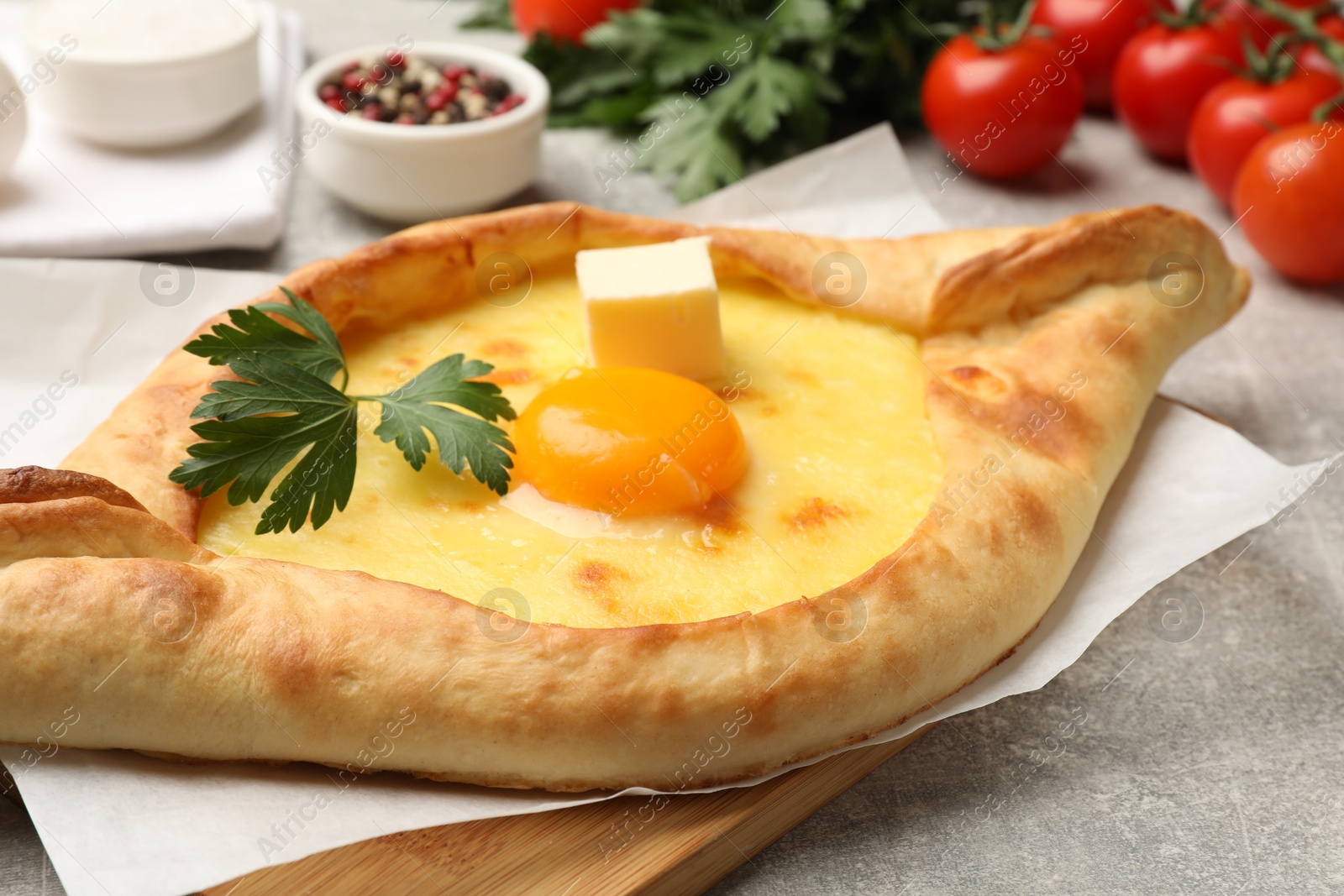 Tasty khachapuri with cheese, egg, parsley and other products on light grey background, closeup Photo of Tasty khachapuri with cheese, egg, parsley and other products on light grey background, closeup