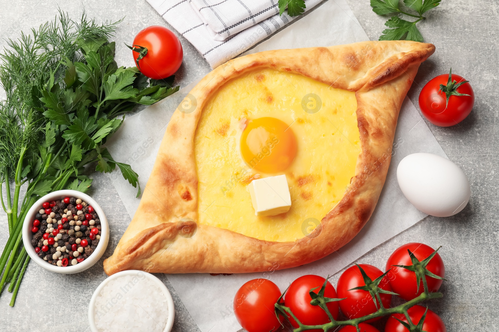 Tasty khachapuri with cheese, egg and other products on light grey background, flat lay Photo of Tasty khachapuri with cheese, egg and other products on light grey background, flat lay