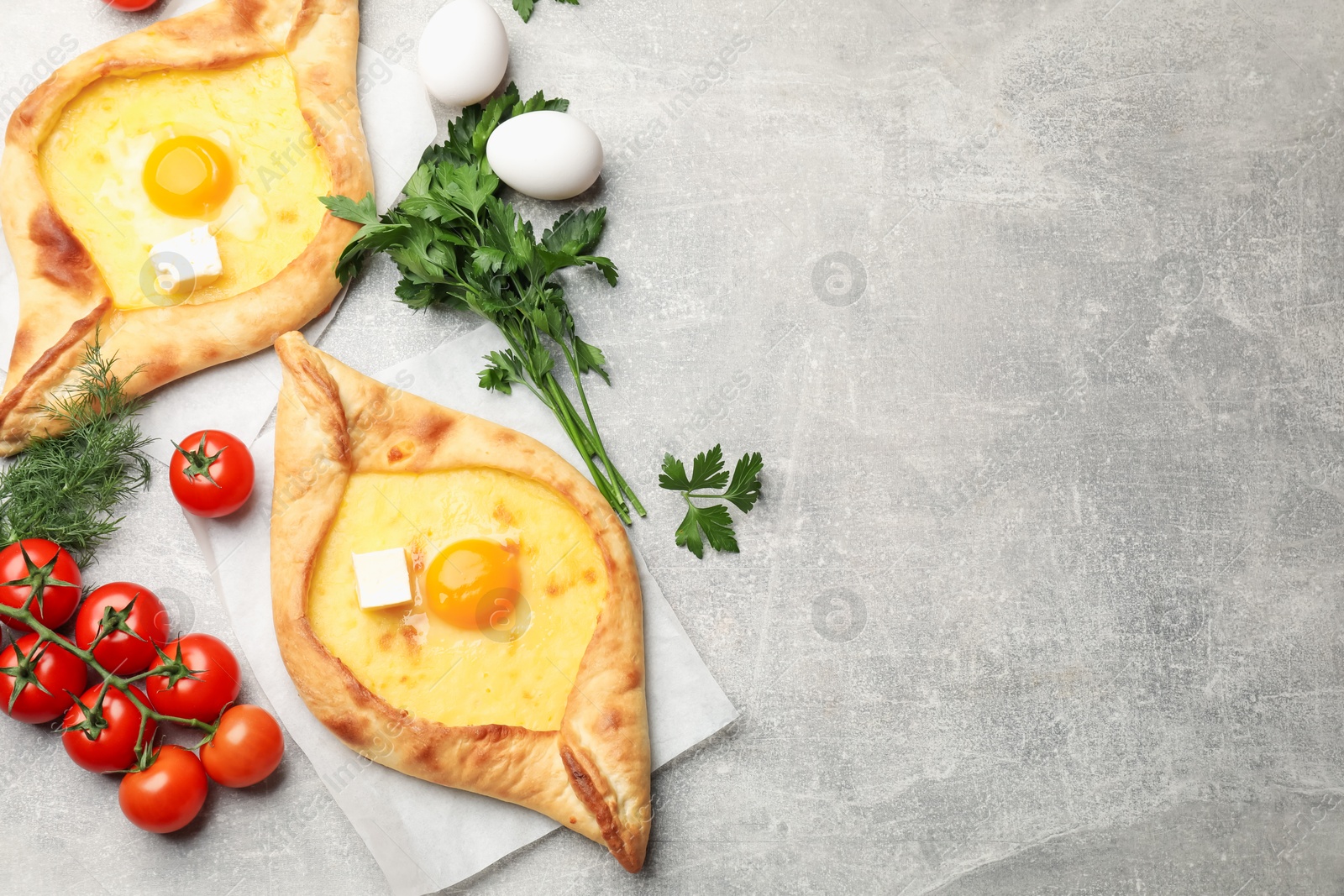 Tasty khachapuri with cheese, egg and other products on light grey background, flat lay. Space for text Photo of Tasty khachapuri with cheese, egg and other products on light grey background, flat lay. Space for text