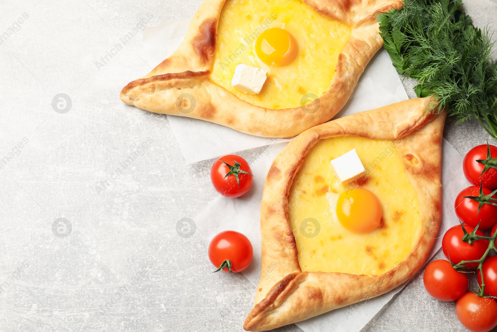 Tasty khachapuri with cheese, egg and other products on light grey background, flat lay. Space for text Photo of Tasty khachapuri with cheese, egg and other products on light grey background, flat lay. Space for text