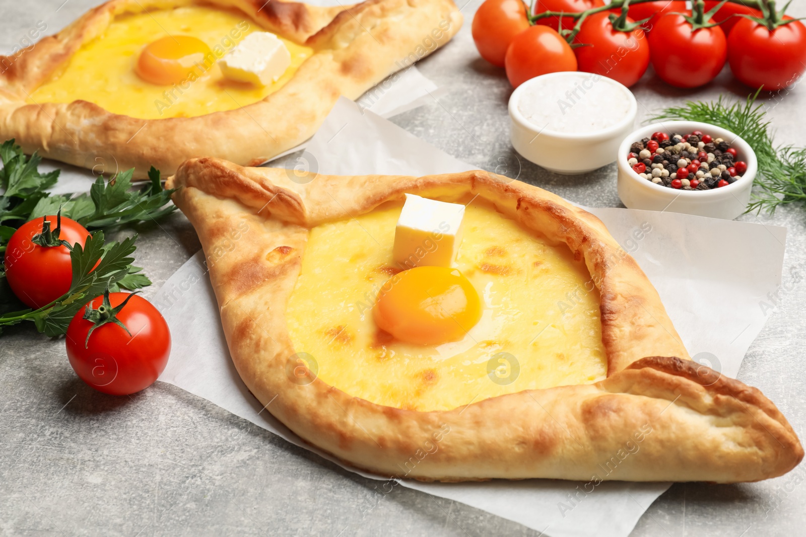 Tasty khachapuri with cheese, egg and other products on light grey background, closeup Photo of Tasty khachapuri with cheese, egg and other products on light grey background, closeup