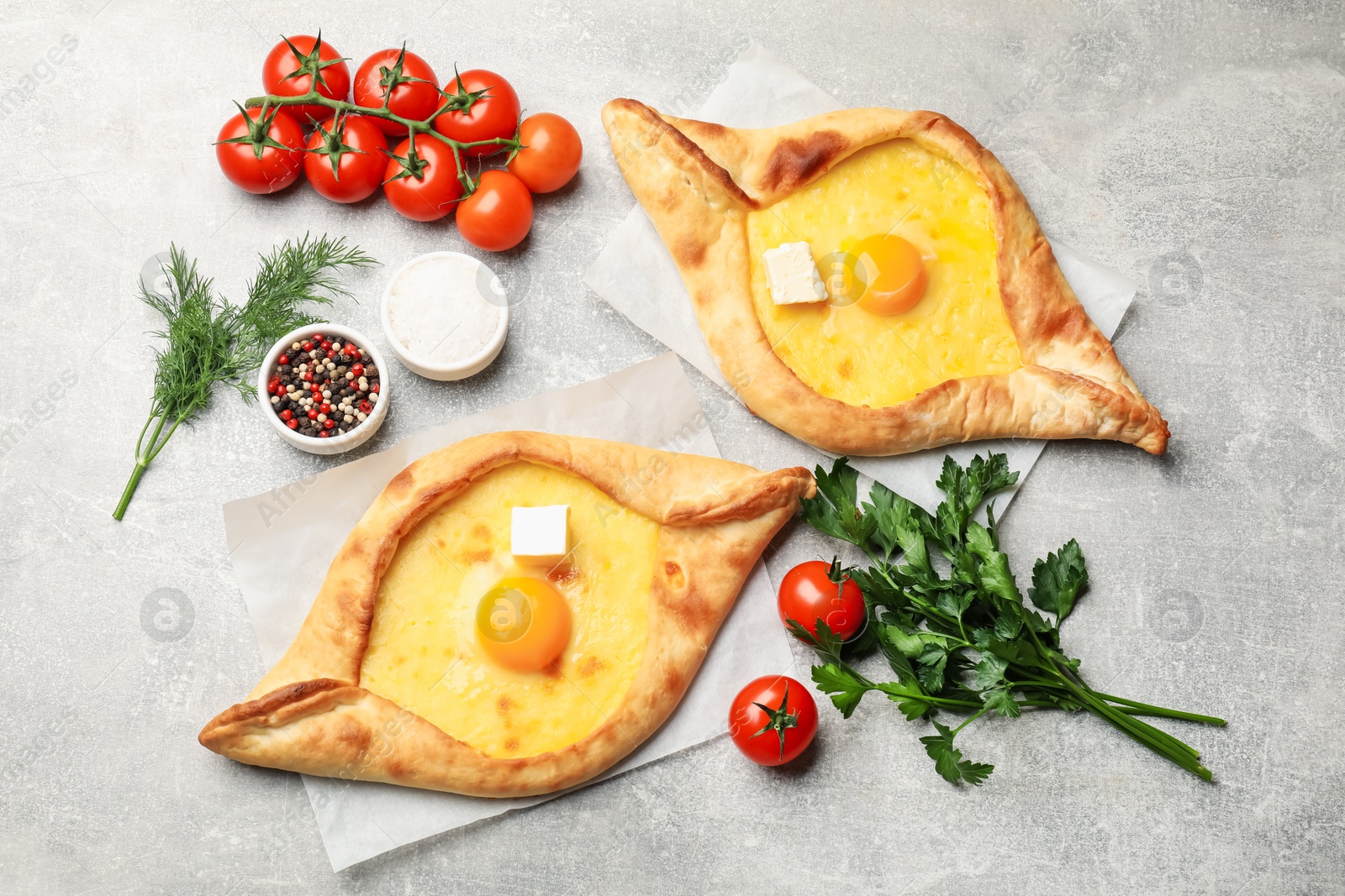 Tasty khachapuri with cheese, egg and other products on light grey background, flat lay Photo of Tasty khachapuri with cheese, egg and other products on light grey background, flat lay
