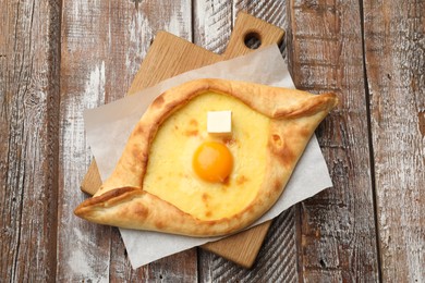 Photo of Tasty khachapuri with cheese and egg on wooden table, top view