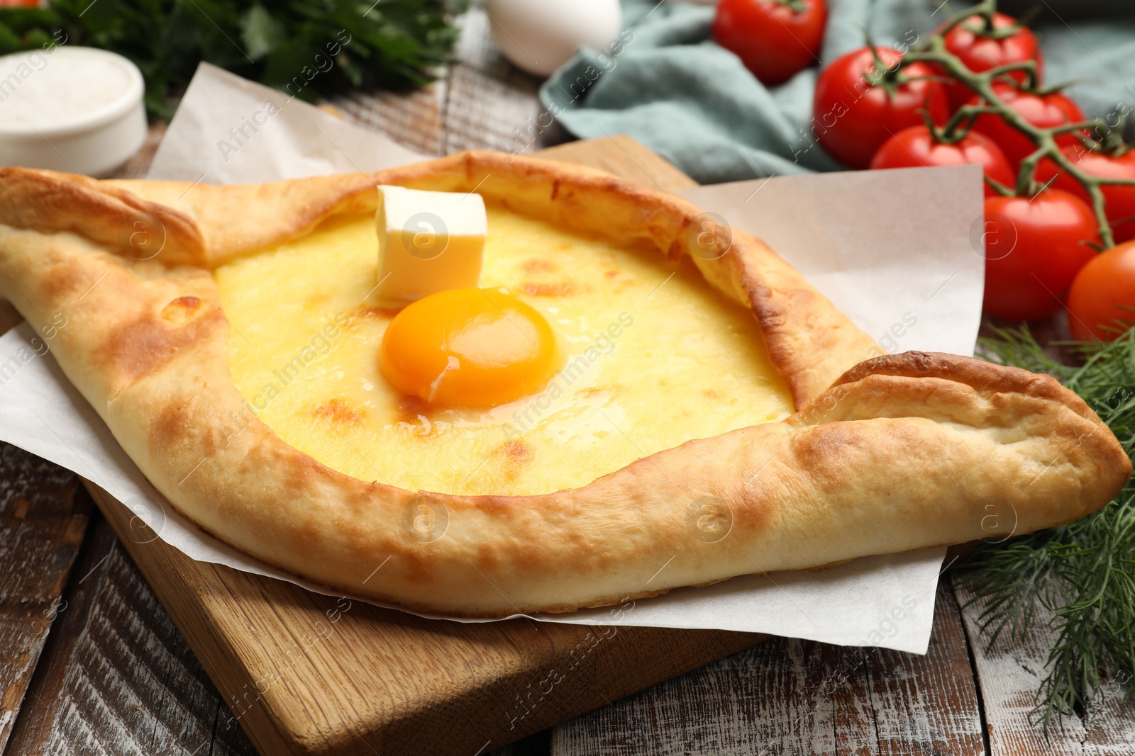 Tasty khachapuri with cheese, egg and other products on wooden table, closeup Photo of Tasty khachapuri with cheese, egg and other products on wooden table, closeup