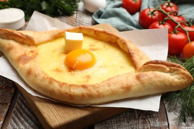 Photo of Tasty khachapuri with cheese, egg and other products on wooden table, closeup