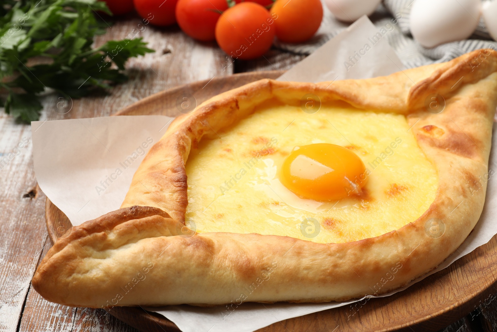 Tasty khachapuri with cheese, egg and other products on wooden table, closeup Photo of Tasty khachapuri with cheese, egg and other products on wooden table, closeup
