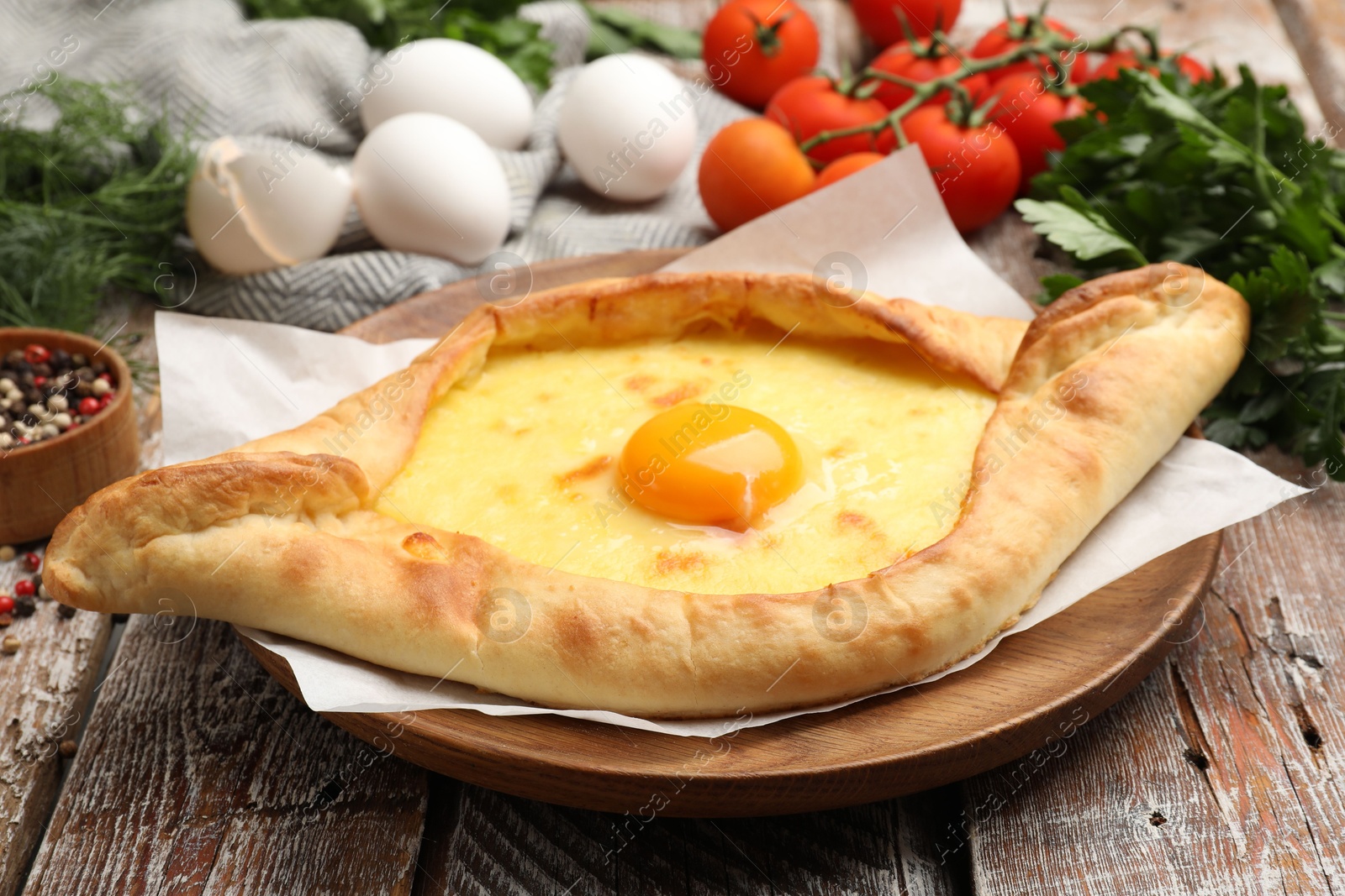 Tasty khachapuri with cheese, egg and other products on wooden table, closeup Photo of Tasty khachapuri with cheese, egg and other products on wooden table, closeup