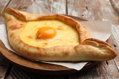 Photo of Tasty khachapuri with cheese and egg on wooden table, closeup