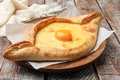 Photo of Tasty khachapuri with cheese and egg on wooden table, closeup