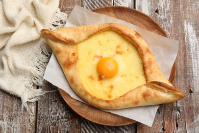 Photo of Tasty khachapuri with cheese and egg on wooden table, top view