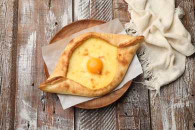 Photo of Tasty khachapuri with cheese and egg on wooden table, top view