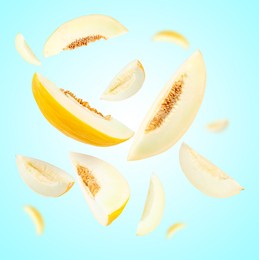 Image of Cut fresh ripe melons swirling in air against light blue background