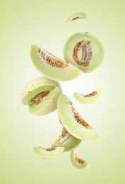 Image of Cut fresh ripe melons swirling in air against light green gradient background