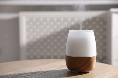 Photo of One stylish aroma lamp on wooden table indoors, closeup. Space for text