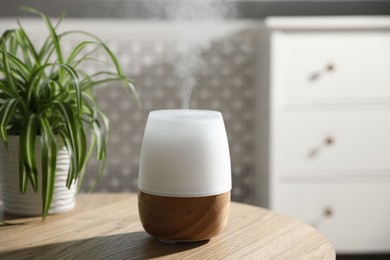 Photo of One stylish aroma lamp and houseplant on wooden table indoors, closeup