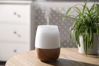 Photo of One stylish aroma lamp and houseplant on wooden table indoors, closeup