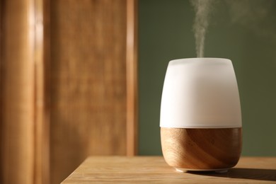 Photo of One stylish aroma lamp on wooden table indoors, closeup. Space for text