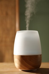 Photo of One stylish aroma lamp on wooden table indoors, closeup