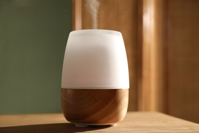 Photo of One stylish aroma lamp on wooden table indoors, closeup