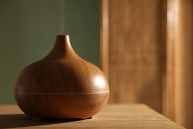 Photo of One stylish aroma lamp on wooden table indoors, closeup. Space for text