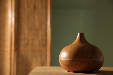 Photo of One stylish aroma lamp on wooden table indoors, closeup. Space for text