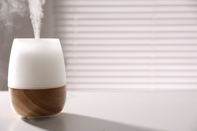 Photo of One stylish aroma lamp on white table indoors, closeup. Space for text