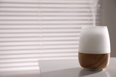Photo of One stylish aroma lamp on white table indoors, closeup. Space for text