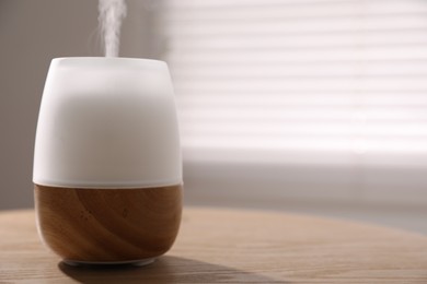 Photo of One stylish aroma lamp on wooden table indoors, closeup. Space for text