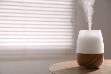 Photo of One stylish aroma lamp on wooden table indoors, closeup. Space for text