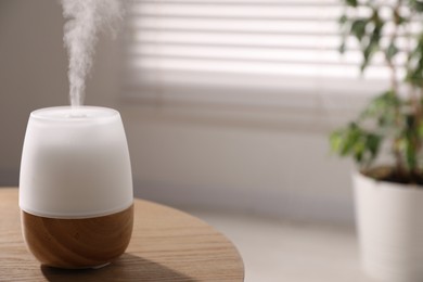 Photo of One stylish aroma lamp on wooden table indoors, closeup. Space for text