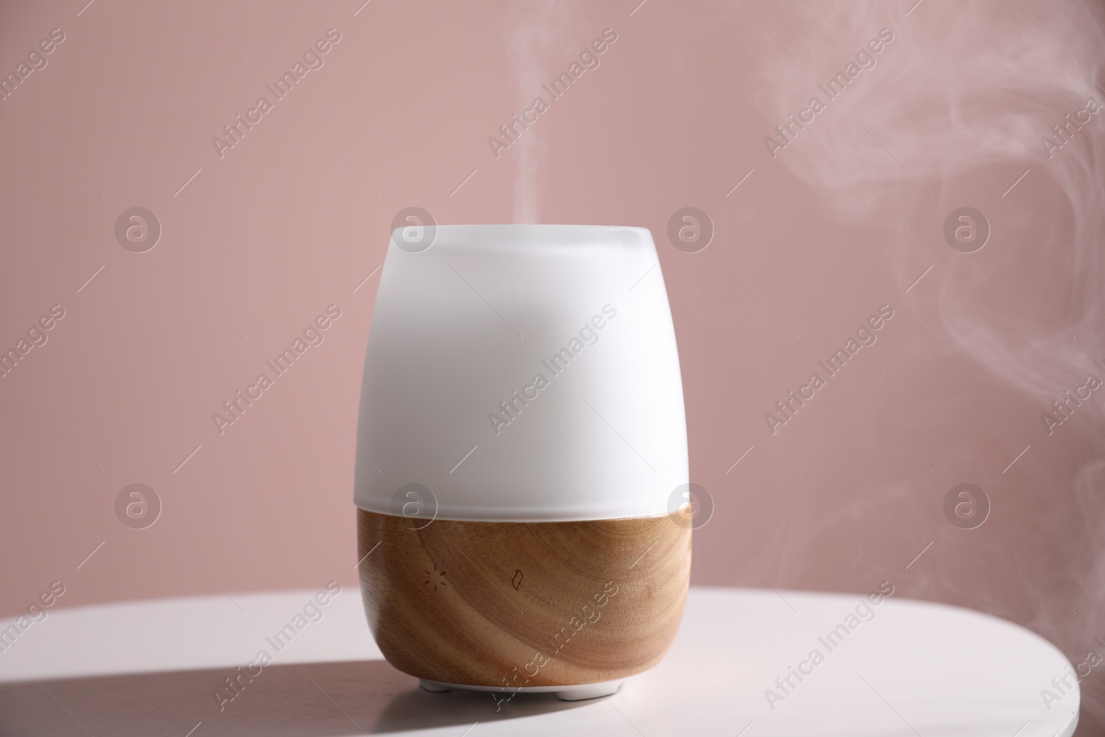 One stylish aroma lamp on white table against pink wall, closeup Photo of One stylish aroma lamp on white table against pink wall, closeup