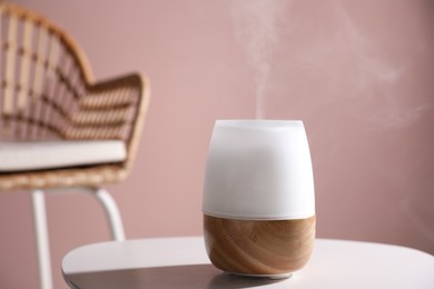 Photo of One stylish aroma lamp on white table against pink wall, closeup