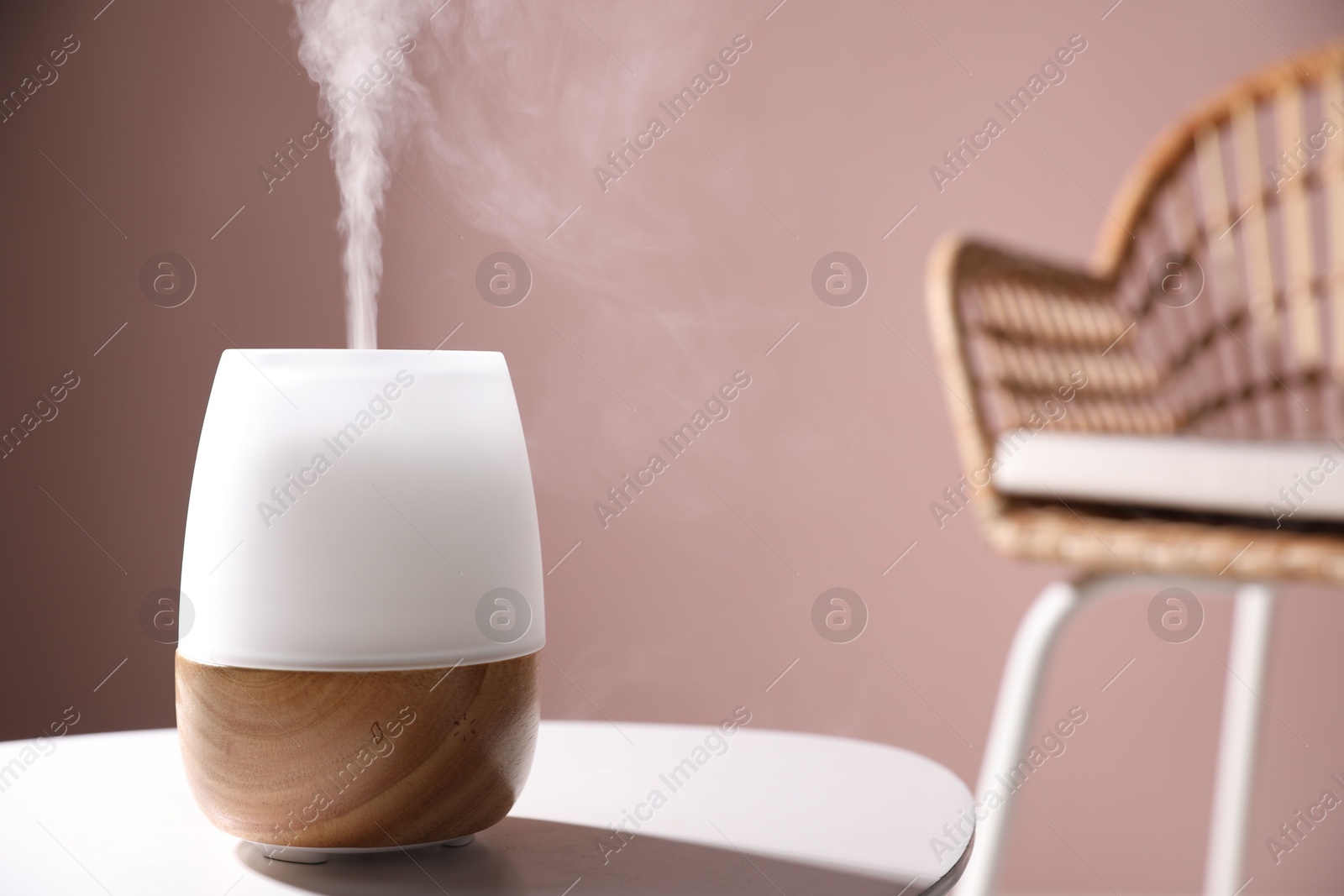 One stylish aroma lamp on white table against pink wall, closeup. Space for text Photo of One stylish aroma lamp on white table against pink wall, closeup. Space for text