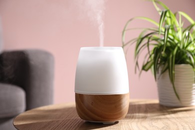 Photo of One stylish aroma lamp and houseplant on wooden table against pink wall, closeup