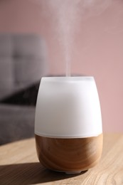 Photo of One stylish aroma lamp on wooden table against pink wall, closeup