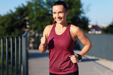 Photo of Athletic young woman in sportswear running outdoors