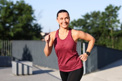 Photo of Athletic young woman in sportswear running outdoors