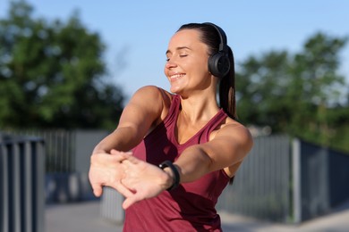 Photo of Athletic young woman with headphones in sportswear before running outdoors