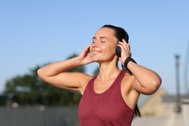 Photo of Athletic young woman with headphones in sportswear before running outdoors